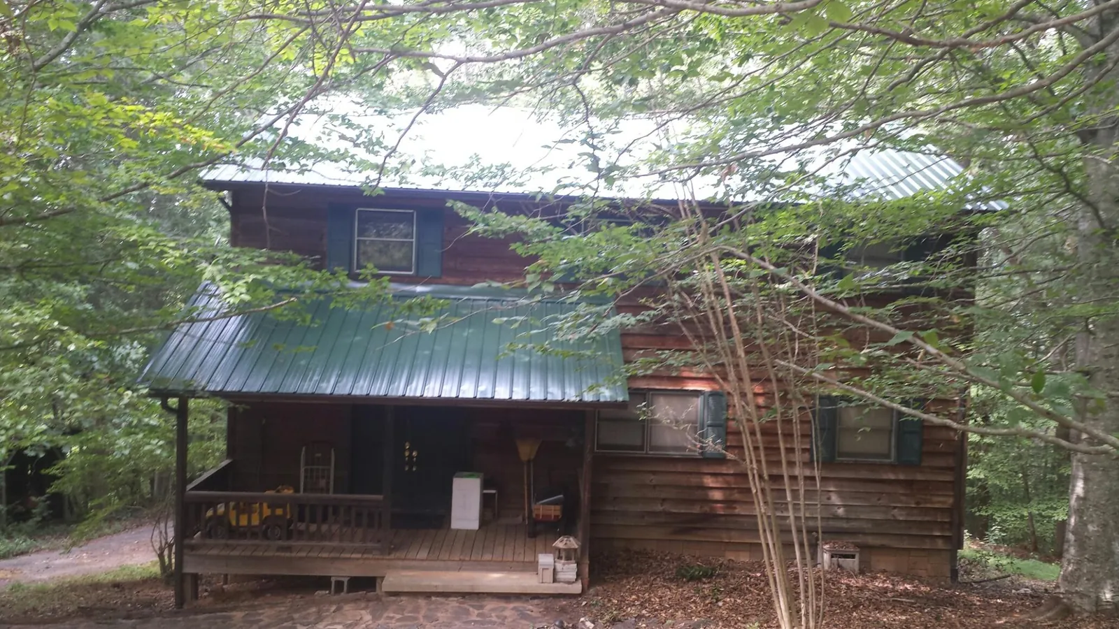 Green metal roof and covered porch on a log cabin in Greenwood